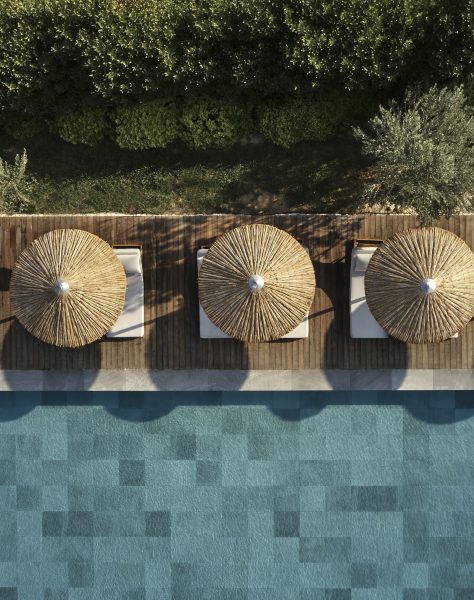 Top-down view of poolside loungers and thatched parasols at Casa Cook Rhodes, offering a tranquil escape at a boutique adults-only hotel in Kolymbia surrounded by natural greenery