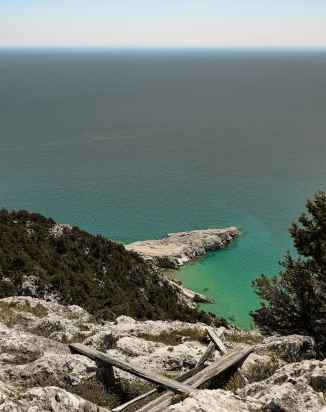 Elevated view of the turquoise sea and rocky coastline from a forested cliffside in Rhodes, capturing the natural beauty surrounding Casa Cook’s boutique adults-only retreat in Kolymbia