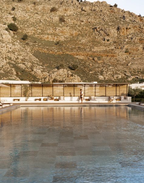 Tranquil poolside scene at Casa Cook Rhodes with sun loungers and shaded cabanas set against a dramatic mountain backdrop, offering a peaceful adults-only retreat in Kolymbia