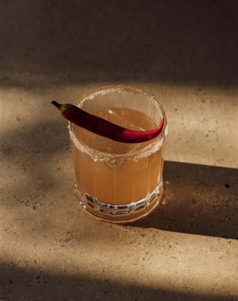 Cocktail with salt rim and red chili garnish