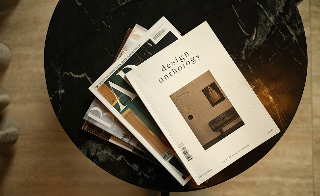 A curated stack of design and architecture magazines — including Design Anthology — fanned out on a round black marble side table at Casa Cook Madonna.