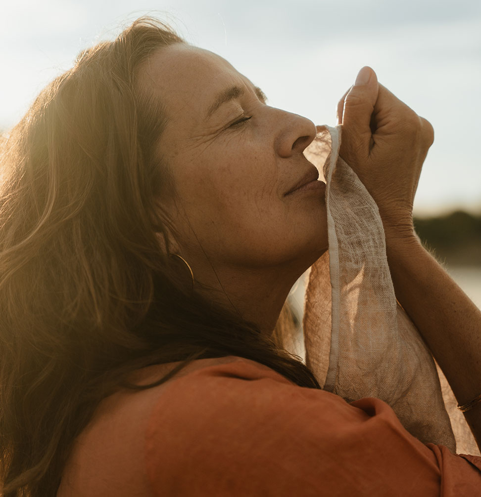 Joy eyes closed facing up the sun holding a cloth to her mouth