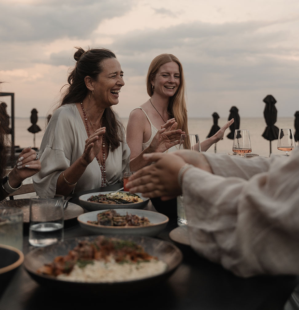 The hosts enjoying dinner with many plates of food on the table for sharing