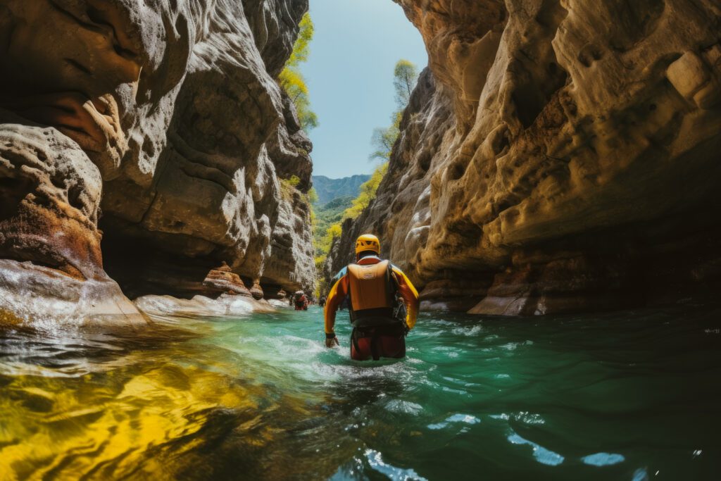 Low angle of a person dressed for canyoning walking through water between two tall rock faces
