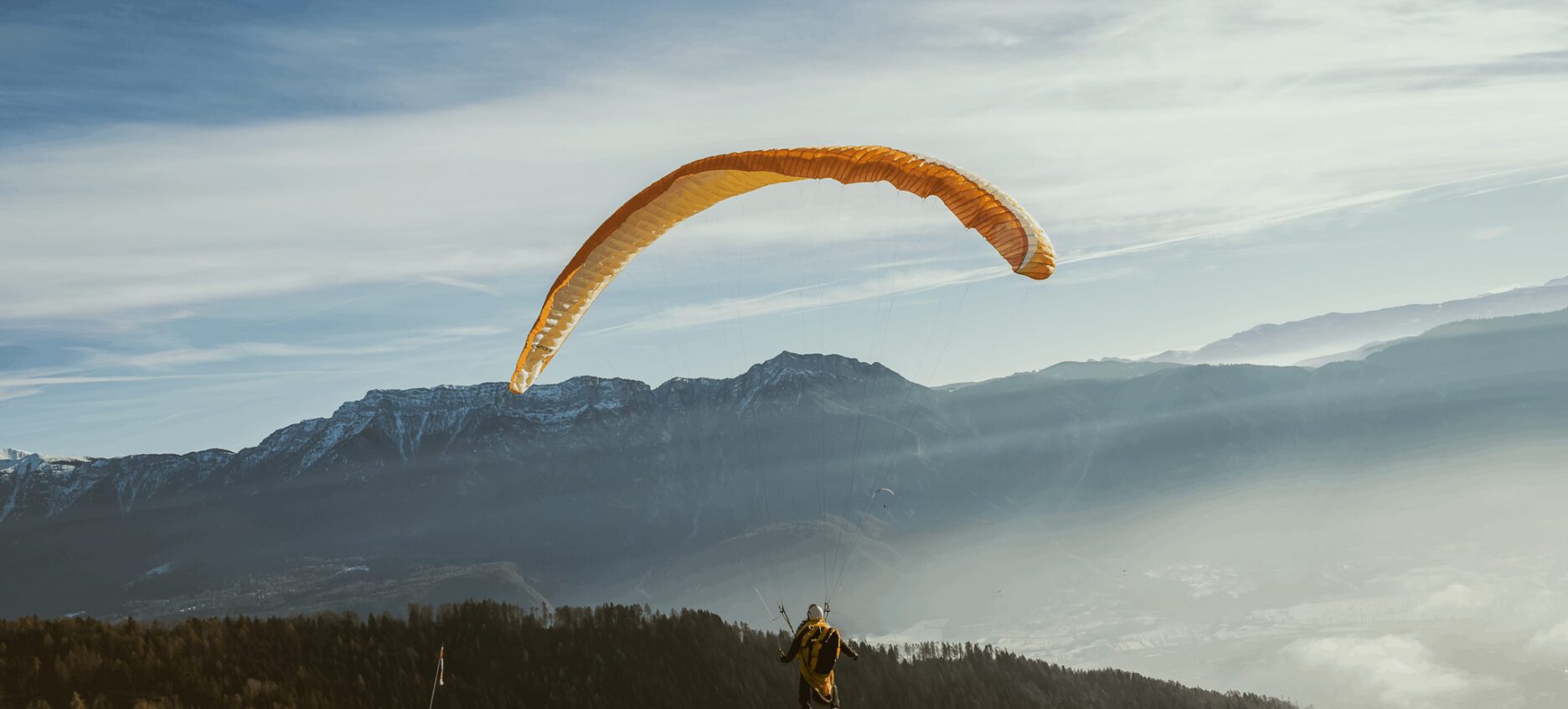 A person landing from paragliding on a clear sunny day.