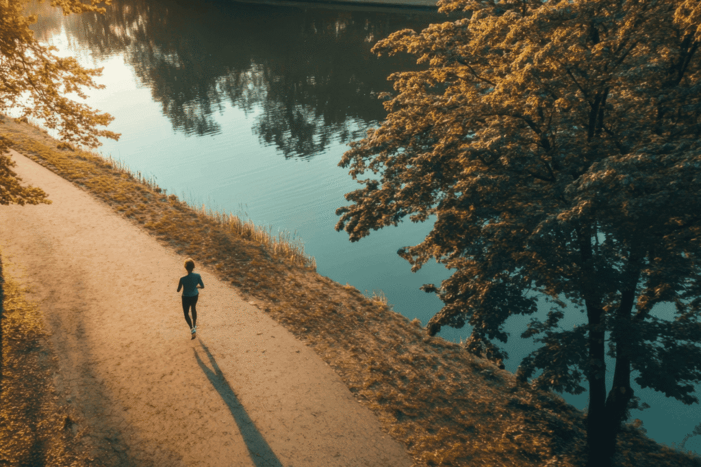 A woman running along side a body of water in the morning sunlight