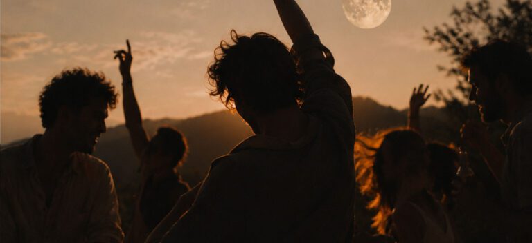 Full moon party, people dancing with their arms up in the air