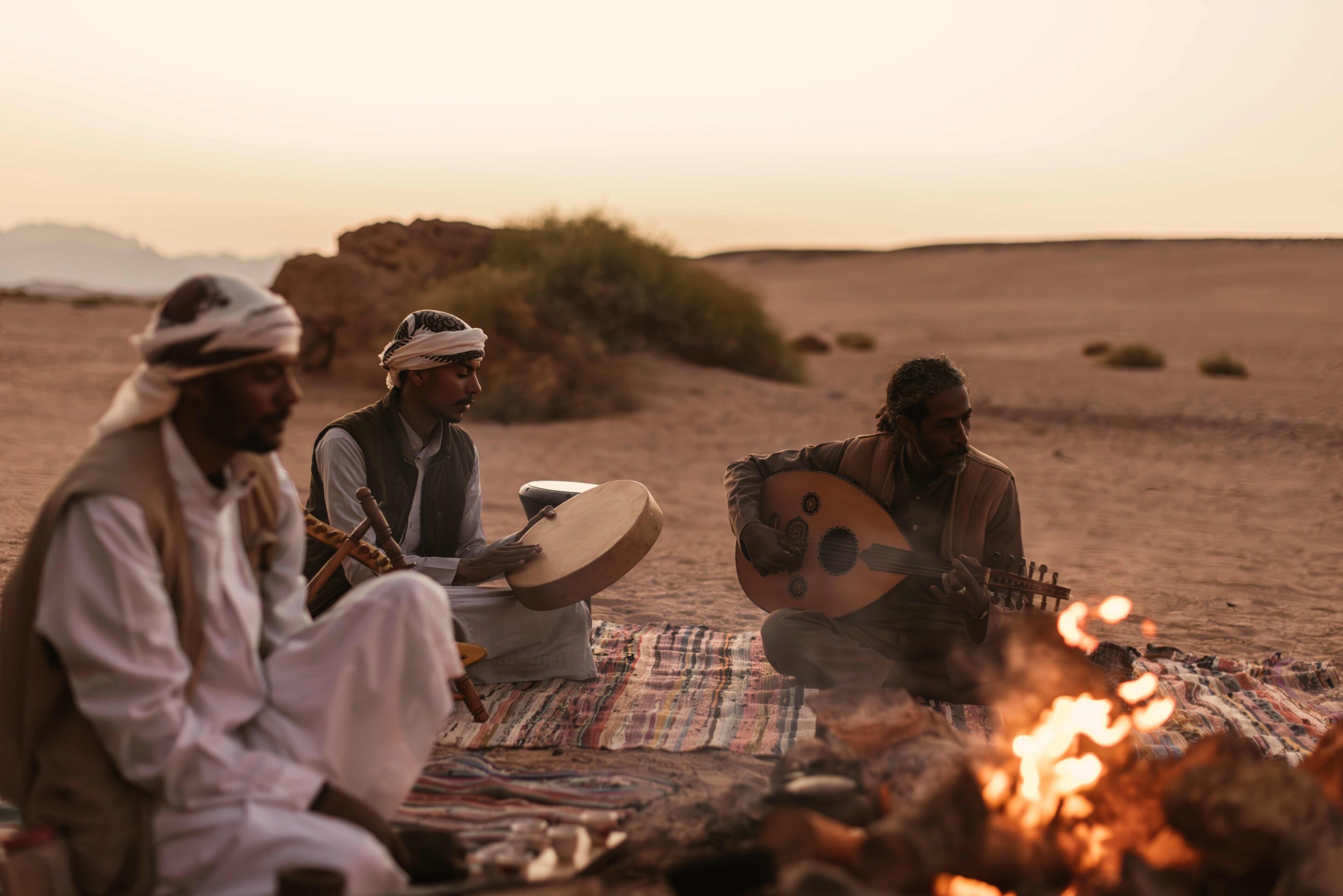 Tour guides setting up a seated area sitting around a fire, playing music as part of the dessert experience